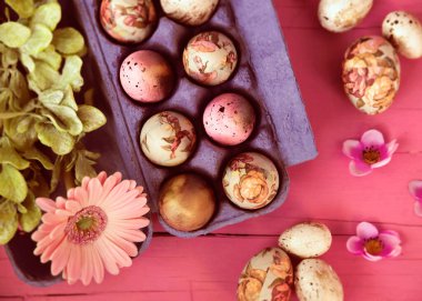 Süslü Paskalya yumurtaları ve çiçekler masada.