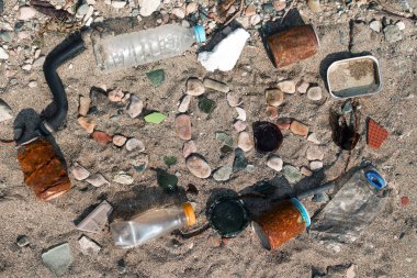 Eski plastik şişelerin, paslı teneke kutuların, cam kırıklarının ve kumdaki diğer çöplerin arasındaki kumsal çakıl taşlarından yapılmış mektuplar.
