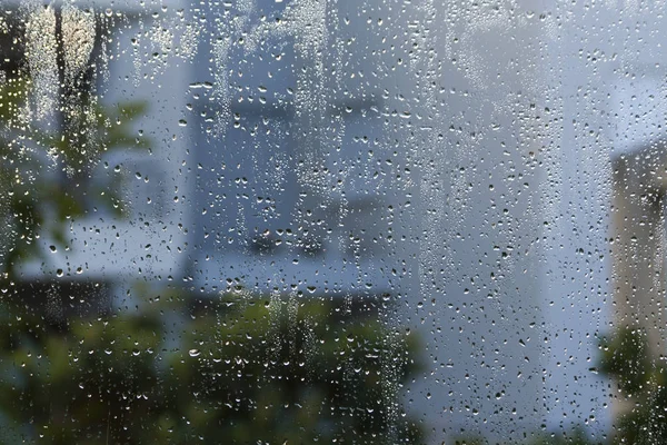 雨滴と淡いグレーと窓ガラス 緑と茶色のブラーと通りのシルエット — ストック写真