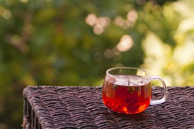 Bahçedeki küçük bir rattan masasında bir bardak sağlıklı bitki çayı.