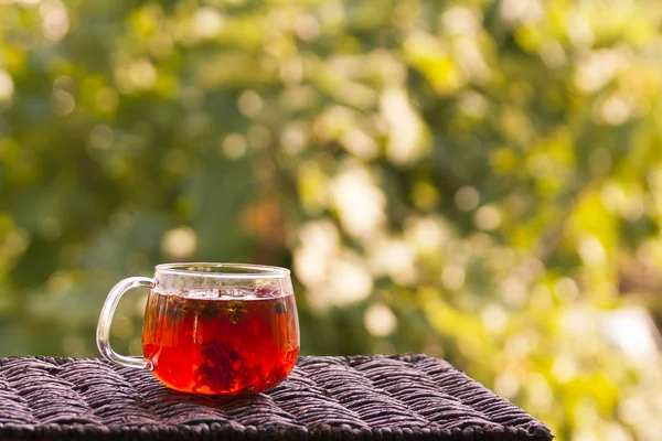 Bahçedeki küçük bir rattan masasında bir bardak sağlıklı bitki çayı.