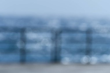 Bulanık arka plan, mavi deniz, gökyüzü ve alacakaranlıkta iskele korkulukları. 