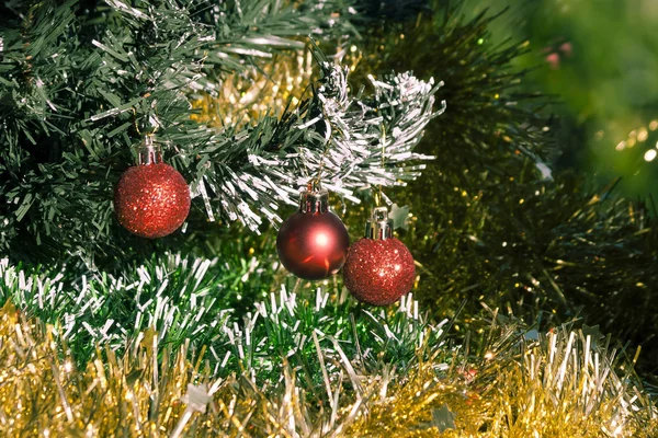 輝く緑と黄金のティンセルに囲まれたクリスマスツリー上の小さな赤い赤ん坊 — ストック写真