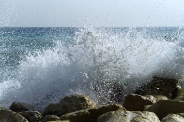 Deniz dalgası beyaz kayalara vuruyor mavi deniz, gökyüzü ve ufukta bir zemin