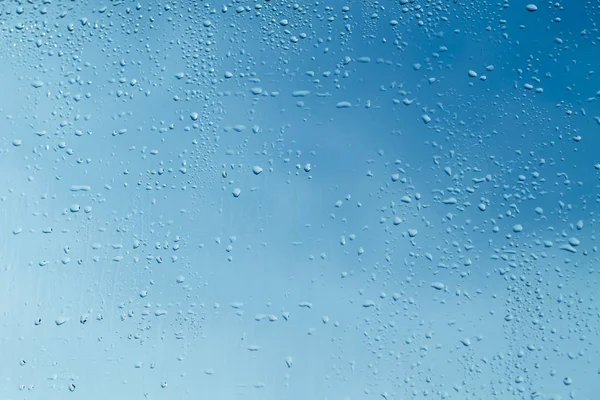 Blue wet window glass with water drops background