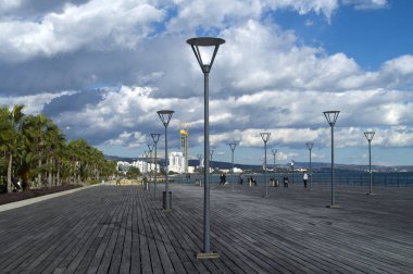 Limasol, Kıbrıs, 27 Aralık 2019: Molos güvertesindeki tahta iskele sokak lambaları, birkaç kişi ve yukarıdaki dramatik gökyüzü