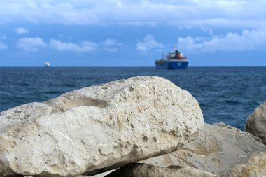 Bulanık mavi deniz, bulutlu gökyüzü ve ufukta gemiler olan beyaz kayalara yakın çekim