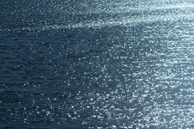 Dalgalanmış mavi deniz suyu yüzeyi, parlak gümüş parıltılarıyla.