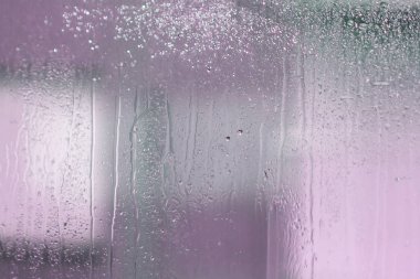 Su damlaları, damlalar ve soyut soluk şekilli ıslak pencere camları.