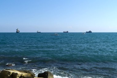Ufukta gemilerin ve balıkçı teknelerinin olduğu panoramik deniz manzarası