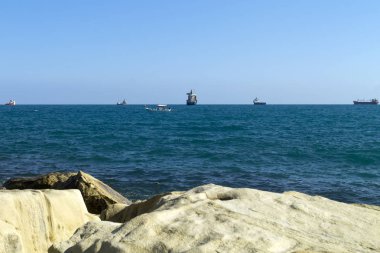 White rocks and the blue sea with boats on the horizon