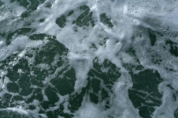 青い海の水面に白い泡と小さな泡のクローズアップ — ストック写真