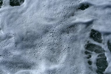 Deniz yüzeyinde beyaz köpük ve küçük kabarcıklar yakın çekim