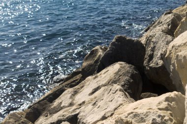Beyaz kayalara yakın çekim ve gün ışığında parlayan mavi deniz.