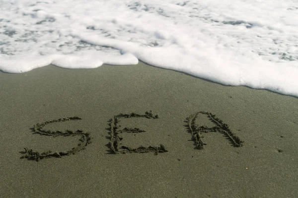 Slovo Moře Napsané Mokrém Písku Pláži Bílou Pěnovou Vlnou — Stock fotografie