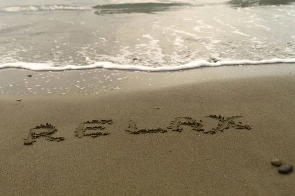 言葉海のビーチでぬれた砂の上に書かれたリラックス — ストック写真