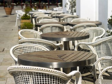 Gün ışığında bir kafede boş masa ve sandalyeler.