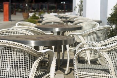 Gün ışığında bir sokak kafesinde boş masa ve sandalyeler.