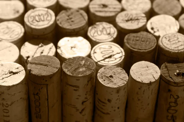 Random selection of used natural wine corks, some of them marked with years of vintage, monochrome brown