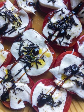 Mozzarella, zeytinyağı ve fesleğenli dilimlenmiş kırmızı domates.
