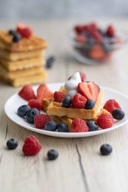 Tahta arka planda taze meyveli Belçika waffle 'ları.