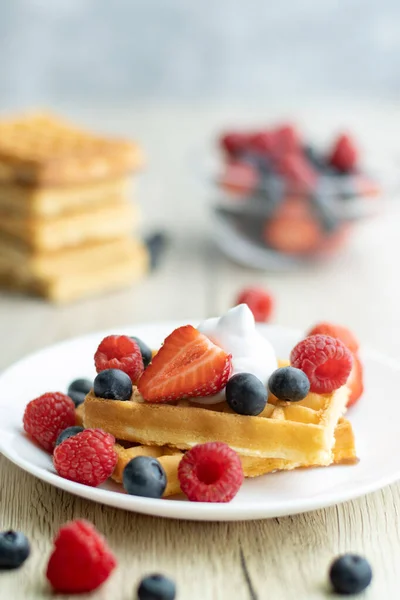 Tahta arka planda taze meyveli Belçika waffle 'ları.