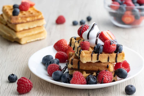 Tahta arka planda taze meyveli Belçika waffle 'ları.