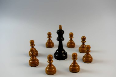 Satranç taşları, siyah papaz beyaz piyonlarla çevrili.