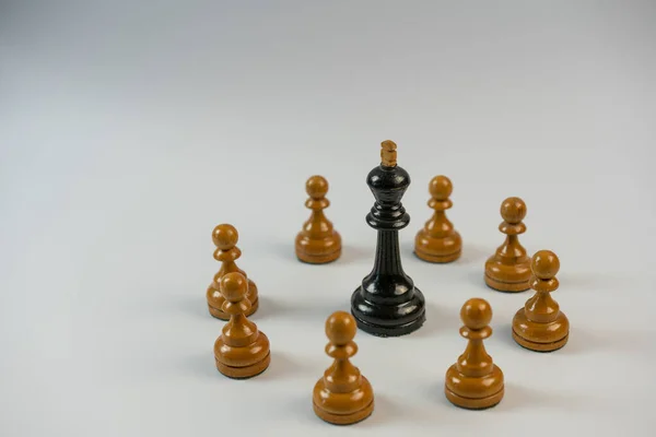 Chess pieces, black king surrounded by white pawns