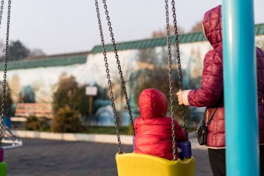 Büyükanne torununu salıncakta sallıyor.