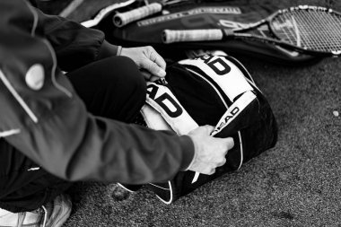 Tenis oyuncusu tenis çantasını bağlıyor.