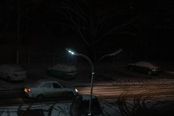 Neve caindo noite contra o fundo de um poste de luz — Fotografia de Stock