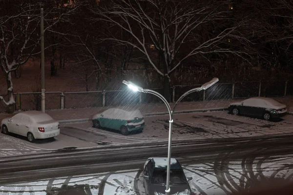 Neve caindo noite contra o fundo de um poste de luz — Fotografia de Stock