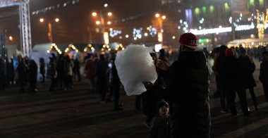 Bir adam pamuk şeker tutuyor, bir çocuk ona bakıyor.