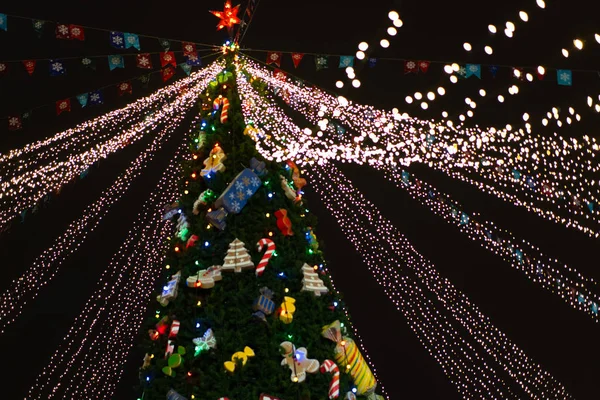 Kerstboom 's nachts versierd met speelgoed en neon lichten — Stockfoto