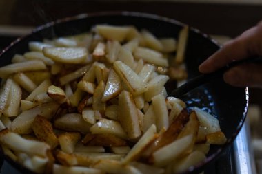 Patatesler tavada kızarır ve spatulayla karıştırılır.