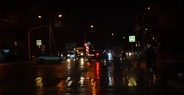 Vägskäl på natten med bilar och människor — Stockfoto