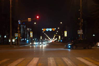 Crossroads at night with a pedestrian crossing, cars and traffic