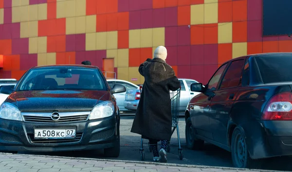 Babcia toczy pusty wózek na ulicy — Zdjęcie stockowe