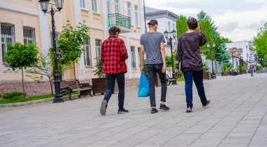 Üç adam caddede yürüyor.