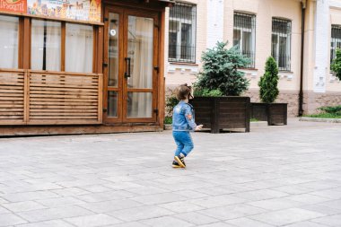 Koruyucu maskeli küçük bir kız sokakta yürüyor.