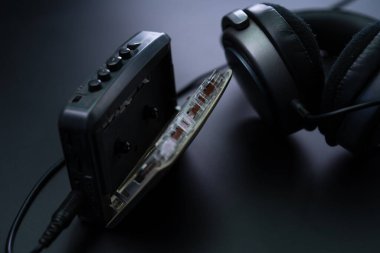 Siyah arka planda kulaklık takan bir kasetçalar.