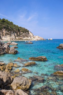 Yunanistan 'da Lefkada, İyon Adaları' nda turkuaz suyu bulunan güzel Agios Nikitas köyünün dikey fotoğrafı.