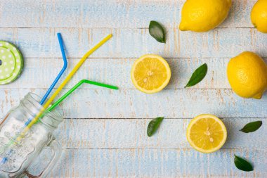 Smoothie kavanozlu düz kompozisyon ve açık mavi ahşap arka planda taze limonlar. Boşluğu kopyala, üst görünüm.