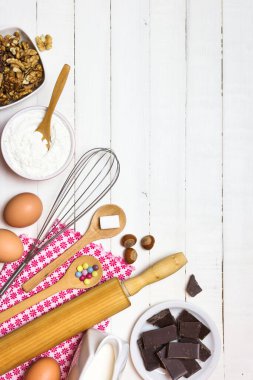 Kek pişirmek için malzemeler ve aletler. Beyaz ahşap masada yumurta, un, süt, şeker, fındık ve çikolata. Pişirme veya pişirme konsepti.