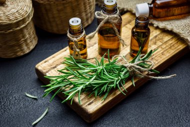 Biberiye bitkisi dalları ve siyah taş arka planda biberiye yağı şişeleri. Bitkisel aromaterapi kavramı.