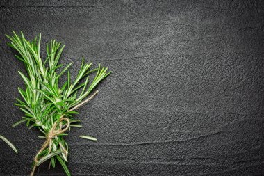 Siyah taş zemin üzerinde taze biberiye dalları. Kopyalama alanı olan üst görünüm.