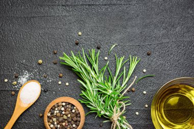 Taze biberiye dalları, siyah taş zemin üzerinde tuz, biber ve zeytin yağı. Kopyalama alanı olan üst görünüm.