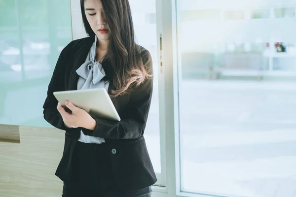 Pazarlama verilerini analiz ederken elinde tablet tutan uzman iş kadını.