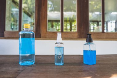 % 70 oranında mavi etil alkol, farklı paketlerde, sprey şişesi, plastik şişe ve jel şişesi, ahşap masadaki koronavirüs koruması için..
